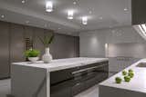 A custom-designed statuary marble kitchen island with sleek white cabinets 