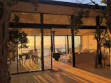 Living Room, Sofa, Two-Sided Fireplace, Ceiling Lighting, and Light Hardwood Floor At sunset the interior environment is bath in warm color and you can appreciate the view and how the light passes from one side to the other  Photo 4 of 8 in Cerro la Higuera House by Rodrigo De la Cerda