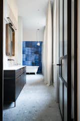 Bath Room, Open Shower, Wood Counter, One Piece Toilet, Drop In Sink, Ceiling Lighting, Terrazzo Floor, Freestanding Tub, Metal Counter, and Porcelain Tile Wall View in to the bathroom  Photo 9 of 10 in Apartment in former sanatorium by studio karhard