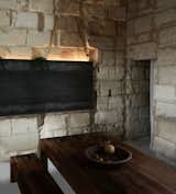 Dining Room, Table, Concrete Floor, Wood Burning Fireplace, Bench, and Wall Lighting  Photo 5 of 11 in Sacré coeur, Stone House by Theo Domini