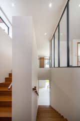 The stairwell features a parapet wall that extends from the ground floor, forming a solid balustrade. A custom wooden handrail is added on top, crafted for a warm, tactile feel that resonates with the home’s overall comfort.