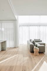 Raw oak floors meet full-height sheer curtains allowing ever-changing shadow play of dappled light.