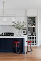 Kitchen and built-in bar, fully equipped with wine holders, benchspace for mixology and shelving backed by a darkened mirror.