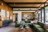 A plush green sectional adds a punchy splash of color to the room's neutral palette. The exposed structural beams extend past the glazing, strengthening the home's outdoor connection.  Photo 4 of 15 in An Architect’s Midcentury Home With Beaming Interiors Asks $1.7M in L.A. from The Takahashi Residence