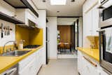 Vibrant yellow formica caps the white cabinetry in the kitchen—a space also fitted with all new stainless steel appliances and further brightened via a skylight.  Photo 8 of 15 in An Architect’s Midcentury Home With Beaming Interiors Asks $1.7M in L.A. from The Takahashi Residence