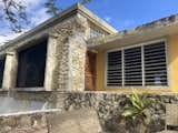 AFTER. As viewed from the brick patio below, a new water-catching roof, new storm and security louvre windows, and mahogany door. Island-vernacular glass block fills an opening above, but allows light in.
