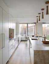 A buff and white kitchen benefits from pops of organize and polished hardware.