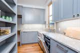 Kitchen, Marble Counter, Undermount Sink, Light Hardwood Floor, Dishwasher, Ceiling Lighting, Wood Cabinet, Wood Backsplashe, and Colorful Cabinet Butler's Pantry  Photo 4 of 7 in Sleek farmhouse with Swiss influences by Courtney Saldivar