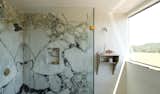 The bathroom is finished with a marble shower that complements the marble countertops in the kitchen. 