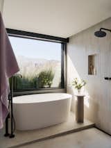 The primary bathroom features a soaking tub, stone slab flooring, and tile from Heath Ceramics.