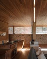 The interior features warm woods, bronze and tan tones, and stone found on the site.