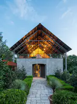 This renovation and addition reimagines an existing home and creates a new guest house, both of which are aesthetically rooted in the wooded, sloping site. The updated home’s design focused on transparency, with a new unimpeded ceiling on the second level that dramatically opens up the interior. The guest house, in contrast, is a simple concrete structure that visually connects to the main home’s concrete base.