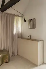 The primary suite bathroom features a Portuguese limestone sink designed by architect Hans Verstuyft, Herzbach fixtures, and Marazzi tiles. 