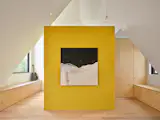 A yellow volume in the middle of the primary bedroom contains the en suite bathroom.