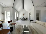The open-plan living and dining area has a vaulted ceiling and numerous windows.