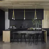 Tricia combined patinated metals with warm woods, limestone plaster, and matte finishes with a  color palette of grays and sandy browns, plus accents of clay and deep green.
