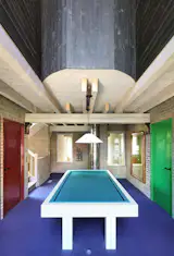 Purple carpeting, red door frames, and a turquoise pool table complete the lively game room.