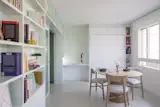 The dining area is defined by white walls, while the storage volume and living space is denoted by mint green .