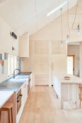 Kitchen, Refrigerator, Wood Backsplashe, Stone Counter, Light Hardwood Floor, Wall Lighting, Range, Pendant Lighting, Range Hood, Dishwasher, Cooktops, Wood Cabinet, Undermount Sink, Ceiling Lighting, and Wall Oven  Photo 8 of 17 in House on a Ridge in Maine by Barrett Made | Maine Architecture + Construction