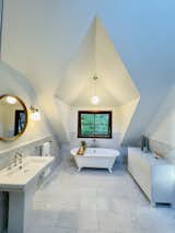 The upper bathroom has been extended into a former attic space where a new dormer and Marvin window make the perfect niche for a classic clawfoot tub, with views of the garden.