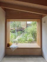 In the bedroom, a large picture window with built-in seating and storage frames the luscious, wild garden.