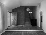 Staircase, Metal Railing, and Wood Tread Before: A dark front entry with dated front door and railings. Small entry to an enclosed kitchen is to the right.  Photo 2 of 24 in Before and After: A Faded Mid-Century Becomes Luminous by HxH Architects PLLC