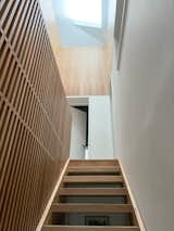 Slatted white oak bookcase diffuses light from the skylights above