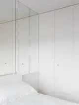 A mirror-clad wall doubles the size of this compact bedroom.