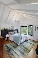 Soaring ceilings are emphasized by the added beams and unique light fixture in this master bedroom.