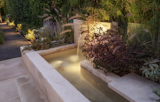 Breezeway garden vignette with fountain and warm landscape lighting that leads you to the backyard.