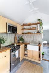 Kitchen, Undermount Sink, Wood Counter, Range, Open Cabinet, Cement Tile Floor, Ceramic Tile Backsplashe, Microwave, Wood Cabinet, and Track Lighting The Shed Bed & Bread  Photo 3 of 20 in The Shed Bed & Bread by South Design Offices