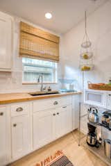 Kitchen, Subway Tile Backsplashe, Microwave, Wood Counter, Refrigerator, Ceiling Lighting, Range, Drop In Sink, Laminate Floor, and White Cabinet  Photo 9 of 16 in West King Cottage by Dustin