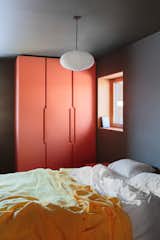  The primary bedroom includes an IKEA wardrobe “hacked” with doors from Noremax in a custom orange color.