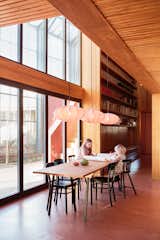 The home is clad in red-painted Norwegian pine, echoing the red-flecked trunks of the surrounding spruce forest. “We wanted to reference a traditional red barn in a modern way and pull it forward into our time and give it a complexity,” says color consultant Dagny Thurmann-Moe. The dining table  is vintage, and the pendants are from IKEA.