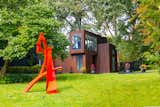 Exterior, Green Roof Material, Wood Siding Material, Flat RoofLine, House Building Type, and Mid-Century Building Type A landscaped garden includes bright sculptures by late artist Brother Mel Meyer.  Photo 11 of 13 in A Restored Midcentury With an 1,800-Square-Foot Addition Seeks $740K in Illinois from Contemporary Mid Century