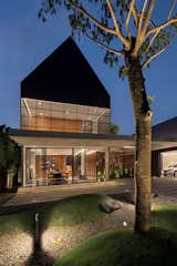 Outdoor, Stone Fences, Wall, Large Pools, Tubs, Shower, Trees, Concrete Patio, Porch, Deck, Front Yard, Wood Patio, Porch, Deck, Swimming Pools, Tubs, Shower, Landscape Lighting, Wood Fences, Wall, and Hanging Lighting Front View  Photo 3 of 64 in Halo House by TAMARA WIBOWO ARCHITECTS INDONESIA