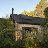 The house appears to be a little cabin in the woods, hidden among the trees.