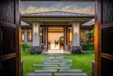 Doors, Wood, Exterior, and Swing Door Type The home ushers in guests through double doors and a lush courtyard straight into an ocean view through the house.   Photo 3 of 8 in Hokulia’s 81-6575 Hia Ai Ono Place by Luxury Design