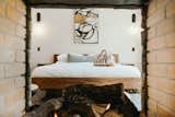 Bedroom, Storage, Accent Lighting, Lamps, Ceiling Lighting, Bed, Concrete Floor, Wall Lighting, and Shelves Open two sided fireplace showcases the well designed master suite.  Photo 8 of 15 in The French Press | Wilderness Escape Among the Pines by François + Melissa