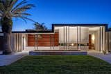 Exterior, House Building Type, Hipped RoofLine, Metal Siding Material, Wood Siding Material, Stone Siding Material, Flat RoofLine, Metal Roof Material, and Stucco Siding Material Evening View from the Street  Photo 4 of 16 in Lear Residence by Lear Studio Architects