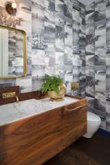 In the powder room, you'll find custom walnut cabinetry from Hart & Toth CabinetryCo., a custom marble sink, VOLA faucet and surfing beach wallpaper.