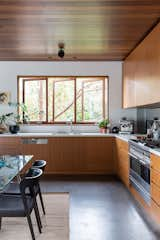 Kitchen, Concrete Floor, Undermount Sink, Engineered Quartz Counter, Mirror Backsplashe, Range, Ceiling Lighting, and Wood Cabinet View of the kitchen and native trees  Photo 3 of 21 in The Balmoral Beach House by Queen Mab Design Studio