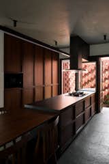 Kitchen, Stone Tile Backsplashe, Refrigerator, Wall Oven, Ceiling Lighting, Range Hood, Limestone Floor, Wood Cabinet, Microwave, Track Lighting, Drop In Sink, and Tile Counter  Photo 12 of 35 in House with Hidden Gardens by Hrishikesh More Architects