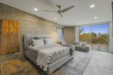 Primary bedroom with concrete walls, flagstone flooring and floor to ceiling sliders.