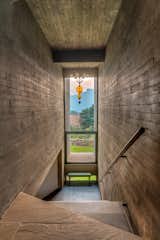 A perforated metal staircase is sandwiched between 2 concrete walls that frame the mountain range in the background called the ‘Duke’s nose’