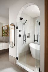 Bath Room, Light Hardwood Floor, Wall Lighting, Granite Counter, Freestanding Tub, Ceramic Tile Wall, Vessel Sink, and Enclosed Shower Similar vibes carried through into the Primary Ensuite with curves in unexpected areas and minimal details. Natural woods and calming cream tones influence a peacefulness into an important room of the house. Being efficient with the small footprint was crucial therefore marrying a full size soaker tub + shower alludes to a much larger Primary room. Not to mention a spa-like environment for the parents of young children.   Photo 5 of 5 in Curve Appeal by Mera Studio Architects