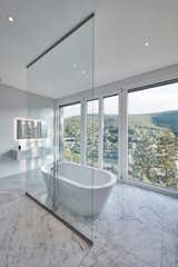 Master bathroom with two cubic carrara marble wash basins, oversized bathtub, spacious rainshower and unobstructed river valley views.