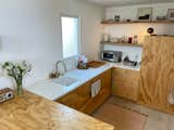 Kitchen, Engineered Quartz Counter, Accent Lighting, Wood Cabinet, Light Hardwood Floor, Undermount Sink, Refrigerator, Cooktops, and Dishwasher The kitchen, with built-in appliances  Photo 3 of 6 in Flatrock House by Kelli Hix