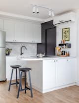 The kitchen was a key point of the project due to our habit of cooking a lot on a daily basis and in our leisure time. So, the choice was not to make a compact kitchen, even with little apartment space. The kitchen needed to be practical, have storage space and also be aesthetically pleasing as it integrates the living room.

We chose to create a light kitchen: all the woodwork is white, the stones are natural and in light tones, and the metals are all black.

The sliding door between the kitchen and the service area was created to create privacy for the area, allowing greater privacy to the common areas — and has a small hole for Louie to pass through to get to his water and food bowls.
