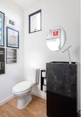 The bathroom downstairs is entirely white, with a sink carved from natural black stone (Negresco) and a white faucet. The wall lamp is mine — Yuri's — own creation and the walls were covered with prints from our collection.

